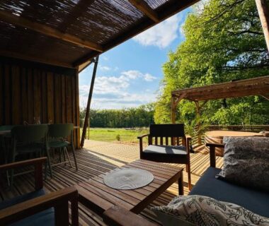 Terrasse en bois avec salon extérieur donnant sur la campagne à La Buissonnière Lodges