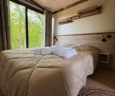 Chambre avec lit et fenêtre sur la végétation à La Buissonnière Lodges
