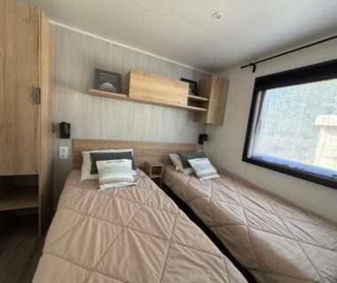 Chambre avec deux lits simples et rangements dans l'hébergement La Cabane