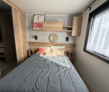 Chambre avec lit et rangements près de la fenêtre au camping La Cabane