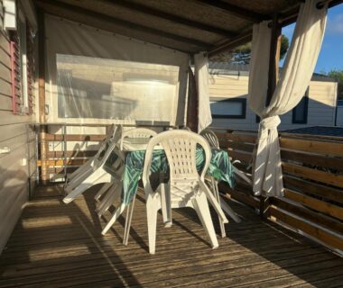 Terrasse couverte avec table et chaises sur plancher en bois au mobilhome La Carabasse