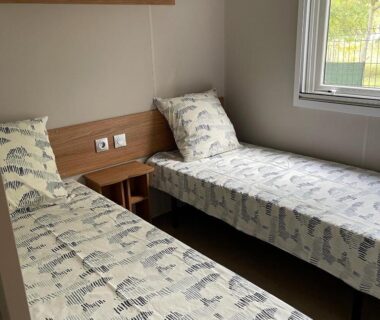 Chambre avec deux lits simples et fenêtre dans le mobilhome La Carabasse Mobilhome Vias plage
