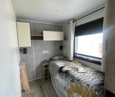 Intérieur chambre avec lit simple et fenêtre dans le mobilhome La Carabasse Mobilhome Vias plage
