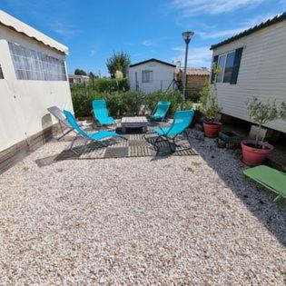Cour gravillonnée avec chaises et table entre mobil-homes à La Cigale Bleue