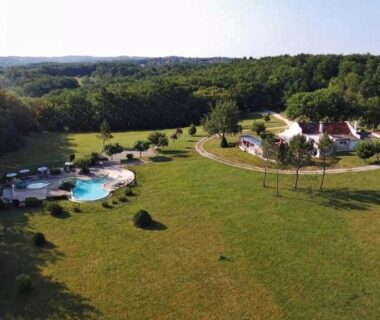 Vue aérienne de la piscine et des emplacements du camping La Clairière Écocamping en vallée de la Dordogne