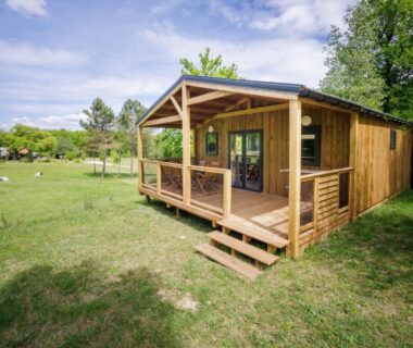 Chalet en bois avec terrasse sur pelouse dans La Clairière écocamping en vallée de la Dordogne