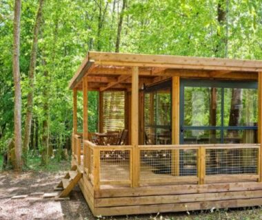 Terrasse couverte en bois au milieu des arbres à La Clairière Écocamping en vallée de la Dordogne