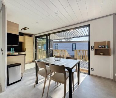 Séjour avec table et kitchenette donnant sur terrasse au camping La Criste Marine