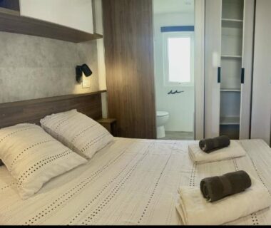 Chambre avec lit double, rangements et serviettes au camping La Dolce Vita