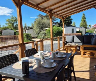 Terrasse en bois avec table dressée et salon extérieur du mobil home La Dolce Vita Méditerranéenne
