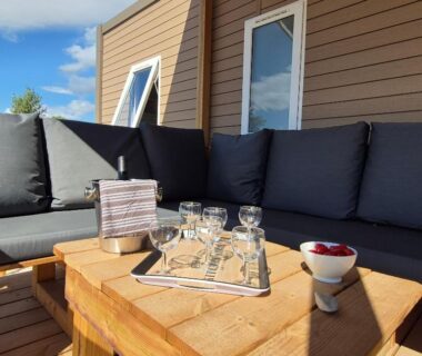 Terrasse en bois avec plateau de verres et canapé au mobil home La Dolce Vita Méditerranéenne