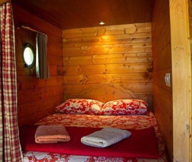 Intérieur en bois avec lit double dans la roulotte La Dorépontaise