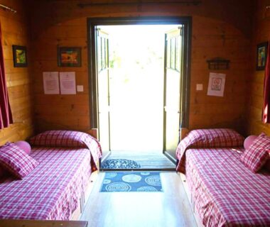 Intérieur de roulotte avec deux lits et porte ouverte vers l'extérieur dans La Dorépontaise ROULOTTE