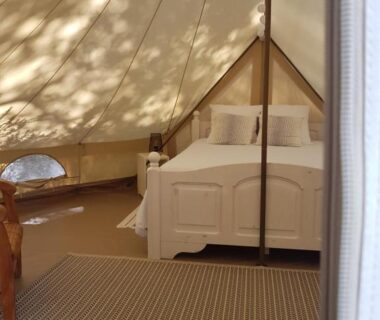 Intérieur de tente avec lit et lampe dans le Glamp'In Lodge Nature de La Ferme de Clareau