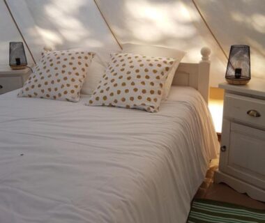 Intérieur de tente avec lit et chevets dans le Glamp’In Lodge Nature à La Ferme de Clareau