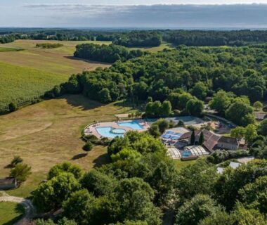 Vue aérienne de la piscine et des chalets dans la campagne à La Forêt Enchantée