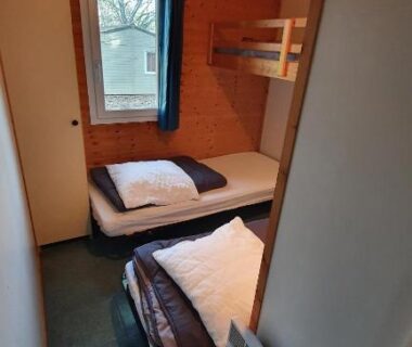 Intérieur de cabine avec lits simples et lits superposés visibles dans le camping La Forêt Enchantée