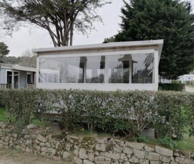 Façade avec véranda vitrée et haie devant La Grande Métairie Location Mobil-Home 4p