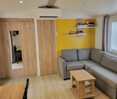 Séjour avec canapé d'angle et table basse dans le mobil home La Lette fleurie