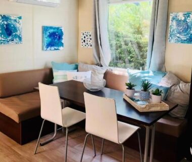 Salon intérieur climatisé avec banquette et table au camping La Paillote de Claire