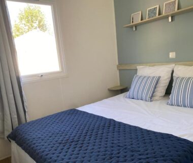 Chambre avec lit et coussins près de la fenêtre au camping La Parenthèse