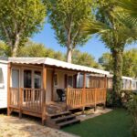 Terrasse en bois et mobil-home sous arbres au camping La Parenthèse