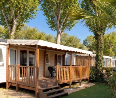 Terrasse en bois et mobil-home sous arbres au camping La Parenthèse