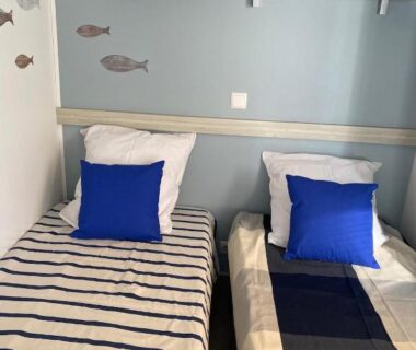 Chambre avec deux lits et coussins bleus à La Parenthèse
