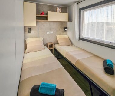 Chambre avec deux lits simples et fenêtre dans le mobil home La Sérénité Normande