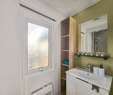 Salle de bain avec lavabo miroir et fenêtre dans La Sérénité Normande