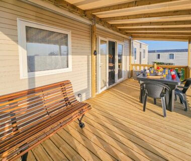 Terrasse en bois devant mobil home avec table chaises et banc du camping La Sérénité Normande