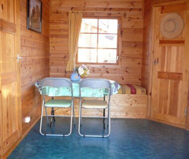 Intérieur en bois avec table deux chaises et banquette dans le chalet La Valière