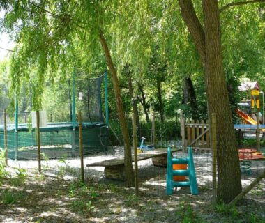 Aire de jeux ombragée avec trampoline et structures ludiques au camping La Valière