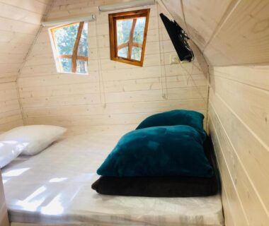 Intérieur en bois avec lit coussins et télévision dans le camping La Vallée De Taradeau