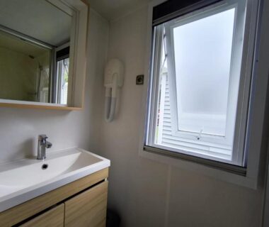 Salle de bain avec lavabo miroir et fenêtre dans le mobil-home La Yole