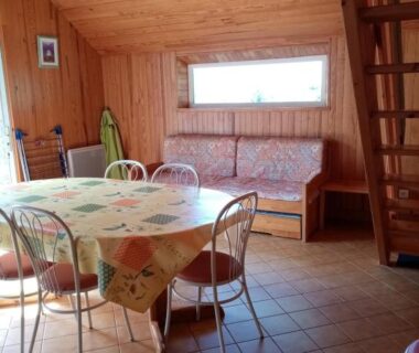 Intérieur séjour en bois avec table chaises et banquette dans le camping La belle étoile