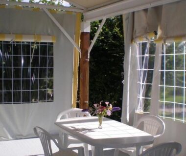 Tonnelle couverte avec table chaises et bouquet au camping La belle étoile