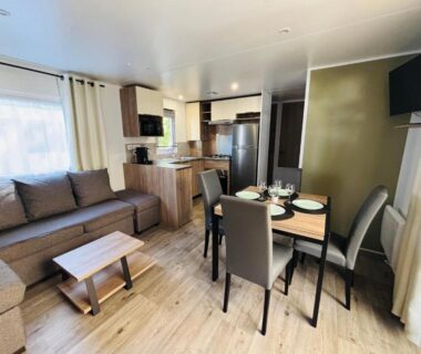 Intérieur de mobil-home avec salon, coin repas et kitchenette dans La belle évasion