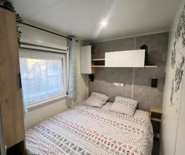 Chambre avec lit double étagères et fenêtre dans La cabane des pins