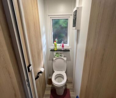 WC étroit avec toilettes fenêtre petit tapis et accessoires dans La cabane des pins