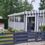 Terrasse et jardin avec salon de jardin et parasol devant le mobil-home de La casa du clos