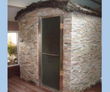 Terrasse en bois avec cabine en pierres et porte vitrée au camping La casa du clos