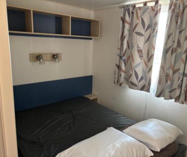 Chambre avec lit et rideaux au camping La palmeraie à Torreilles