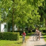 Allée arborée avec cyclistes et mobil-homes au camping La pépite Rose d’Europapark
