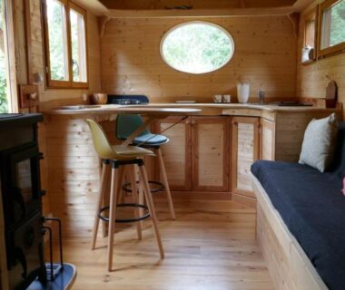 Intérieur en bois avec coin cuisine et banquette de la roulotte aux Nuits Insolites d'Argoumbat