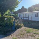 Terrasse et entrée de mobil-home entourées de haies au camping La terrasse du chat