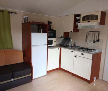 Intérieur kitchenette avec réfrigérateur et canapé dans le mobil home du camping La terrasse du chat