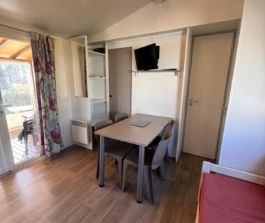 Intérieur du mobil home avec table et télévision du Lac Des Rêves LaConciergerieByNina