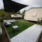 Terrasse extérieure avec salon de jardin et parasol du mobil home Lac des rêves