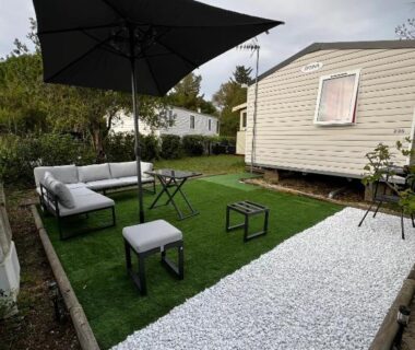 Terrasse extérieure avec salon de jardin et parasol du mobil home Lac des rêves